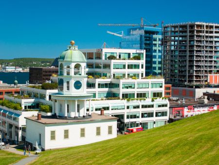 Halifax's historic Citadel Hill Clocktower surrounded by modern buildings on a sunny day, including the Nova Centre under construction.